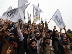 Men wave the flag of the Islamic Emirate of Afghanistan during a celebration of the first anniversary of the Taliban's return to power on August 15, 2022 in Kabul.