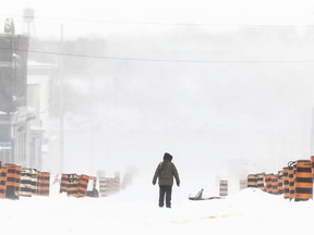 強風と大量の雪をもたらす初冬の嵐の中、オンタリオ州フォート エリーの通りを歩く男性。 2022 年 1 月 19 日。