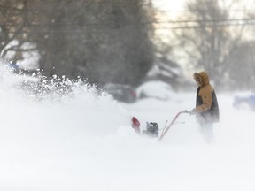 A man uses a snowblower in Fort Erie, Ont., during an early winter storm that delivered high winds and large amounts of snow across southern Ontario and western New York, Saturday, Nov. 19, 2022.