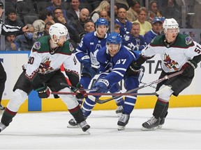 Pierre Engvall of the Toronto Maple Leafs battles for the puck between J.J. Moser and Troy Stecher of the Arizona Coyotes during an NHL game at Scotiabank Arena on October 17, 2022 in Toronto, Ontario, Canada.