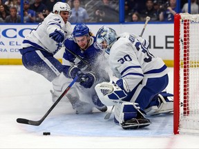 Anthony Cirelli of the Tampa Bay Lightning is checked by John Tavares of the Toronto Maple Leafs as they crash into Matt Murray during the second period of the game at the Amalie Arena on December 3, 2022 in Tampa, Florida.