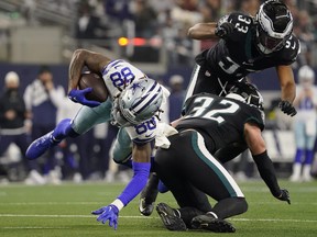 CeeDee Lamb of the Dallas Cowboys runs the ball after a catch and tackled by Reed Blankenship of the Philadelphia Eagles during the first half at AT&T Stadium on December 24, 2022 in Arlington, Texas.