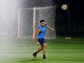 Argentina's Marcos Acuna during training as a sprinkler sprays.