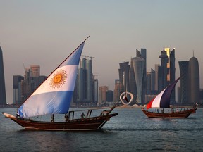 Boats with sails showing the flags of the nations Argentina and France sail in-front of the Doha skyline.