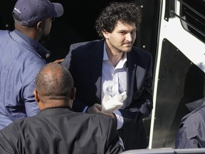 FTX founder Sam Bankman-Fried, center, is escorted from a Corrections Department van as he arrives at the Magistrate Court building for a hearing, in Nassau, Bahamas, Wednesday, Dec. 21, 2022.