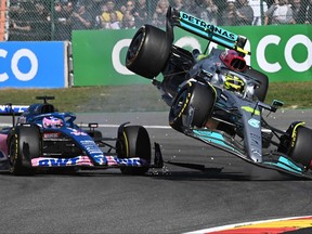 Mercedes' British driver Lewis Hamilton (R) collides with Alpine's Spanish driver Fernando Alonso (C) during the Belgian Formula One Grand Prix at Spa-Francophones racetrack at Spa, on August 28, 2022.