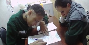 This video grab taken from a footage shown on December 8, 2022 by Russian state media that AFP couldn’t independently authenticate shows U.S. basketball star Brittney Griner (L) filling documents before to be freed from prison in Moscow. (Photo by Russian State Media/AFP via Getty Images)