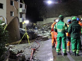 This video grab taken from a footage released on December 12, 2022 by the Government of Jersey shows fire crews standing in front of the rubble of a low-rise apartment building after an explosion, in the Channel island's port capital Saint Helier.