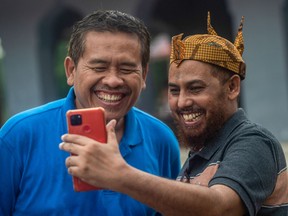 Umar Patek (R), one of the bombmakers in the Bali blasts that killed more than 200 people 20 years ago, takes a selfie with Ali Fauzi (L), a brother of three of the Bali bombers and set up a foundation to help former prisoners rejoin society, at Tenggulun village in Lamongan on December 13, 2022.