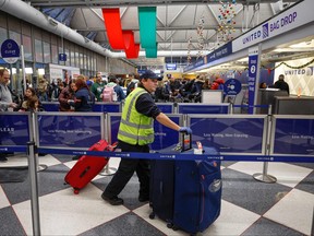 A United Airlines employee pushes luggage at Terminal 1 ahead of the Christmas Holiday at O'Hare International Airport on Dec. 22, 2022, in Chicago.