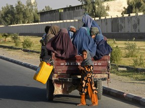 Afghan burqa-clad women travel in a vehicle along the road in Kandahar on December 25, 2022.