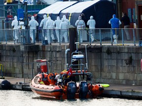 Police forensics officers wearing protective gear walk at the Port of Dover after a small boat loaded with migrants capsized in the English Channel, in Dover, Britain Dec. 14, 2022.
