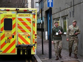 Members of the military walk next to an ambulance, on the day ambulance workers strike amid a dispute with the government over pay, near the NHS London Ambulance Service, in London, Dec. 21, 2022.