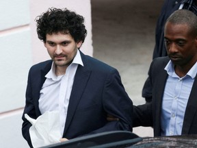 Sam Bankman-Fried, the founder and former CEO of crypto currency exchange FTX, is escorted out of the Magistrate Court building in Nassau, Bahamas, Dec. 21, 2022.