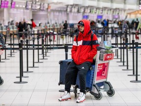 A person sits on his luggage during a winter storm at Toronto Pearson International Airport, Dec. 23, 2022.