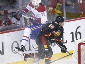 Montreal Canadiens' Arber Xhekaj, left, collides with Calgary Flames' Andrew Mangiapane behind the net during first period NHL hockey action in Calgary, Thursday, Dec. 1, 2022.
