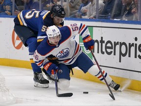 Edmonton Oilers' Kailer Yamamoto and St. Louis Blues' Colton Parayko chase after a loose puck along the boards during the third period of an NHL hockey game Wednesday, Oct. 26, 2022, in St. Louis.