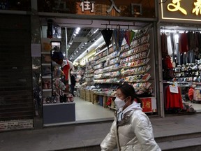 A person walks past shops after the government eased curbs on COVID-19 control, in Wuhan, Hubei province, China, Saturday, Dec. 10, 2022.