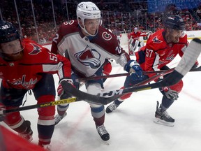 Matt Irwin (52) and Trevor van Riemsdyk (57) of the Washington Capitals go after the puck against Dryden Hunt (22) of the Colorado Avalanche on Nov. 19, 2022. The Leafs will be Hunt’s third NHL team in 2022-23 .