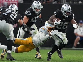 Las Vegas Raiders running back Josh Jacobs carries the ball against Los Angeles Chargers safety Derwin James Jr. in the second half at Allegiant Stadium.