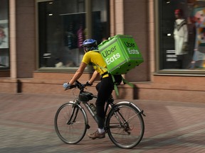 An Uber Eats food courier rides on bike for delivery.
