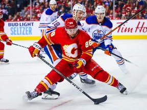 Calgary Flames left wing Andrew Mangiapane and Edmonton Oilers left wing Zach Hyman battle for the puck during the third period at Scotiabank Saddledome.
