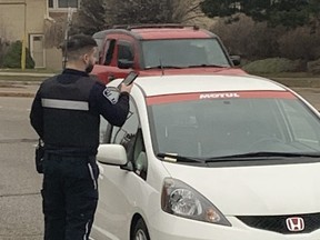 A Parking Enforcement Officer issues a ticket at a school drop-off area on Glen Erin Dr. on Tuesday, Dec. 6, 2022.