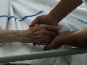 A file picture taken on July 22, 2013 shows a nurse holding the hand of an elderly patient at the palliative care unit.