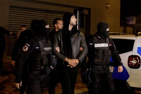 Andrew Tate and Tristan Tate are escorted by police officers outside the headquarters of the Directorate for Investigating Organized Crime and Terrorism in Bucharest (DIICOT) after being detained for 24 hours, in Bucharest, Romania, December 29, 2022. Inquam Photos/Octav Ganea via REUTERS