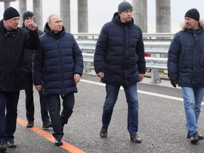 Russian President Vladimir Putin listens to Deputy Prime Minister Marat Khusnullin as he visits a bridge connecting the Russian mainland with the Crimean Peninsula across the Kerch Strait, December 5, 2022.