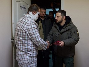 Ukraine's President Volodymyr Zelenskyy shakes hands with an injured service member as he visits a hospital on the Day of the Ukrainian Armed Forces, amid Russia's attack on Ukraine, in Kharkiv, Ukraine Tuesday, Dec. 6, 2022.
