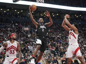 L.A. Clippers forward Kawhi Leonard (2) goes up to make a basket against Toronto Raptors guard Gary Trent Jr. (33) and forward Scottie Barnes (4) during the second half at Scotiabank Arena.