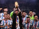 Argentina's captain and forward #10 Lionel Messi (C) lifts the FIFA World Cup Trophy on stage as he celebrates with teammates after they won the Qatar 2022 World Cup final football match between Argentina and France at Lusail Stadium in Lusail, north of Doha on December 18, 2022.