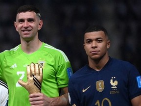 In this file photo taken on December 18, 2022, Argentina's goalkeeper Emiliano Martinez and France's forward Kylian Mbappe pose on the podium after receiving the Golden Glove and Golden Boot awards respectively, during the Qatar 2022 World Cup trophy ceremony after the football final match between Argentina and France at Lusail Stadium in Lusail, north of Doha.