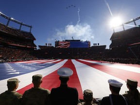 Members of the U.S. military hold an American flag during the national anthem before a game between the Denver Broncos and the Las Vegas Raiders at Empower Field At Mile High on November 20, 2022 in Denver, Colorado.