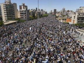 Argentine soccer fans crowd a highway for a homecoming parade for the Argentine soccer team that won the World Cup tournament in Buenos Aires, Argentina, Tuesday, Dec. 20, 2022.