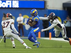 Los Angeles Rams running back Cam Akers runs between Denver Broncos cornerback Damarri Mathis, left, and linebacker Randy Gregory during the first half of an NFL football game between the Los Angeles Rams and the Denver Broncos on Sunday, Dec. 25, 2022, in Inglewood, Calif.