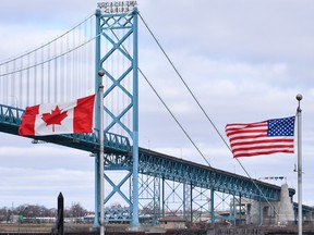 Canadian and American flags fly near the Ambassador Bridge at the Canada-USA border crossing in Windsor, Ont. on Saturday, March 21, 2020.