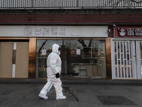 An epidemic control worker wears PPE to prevent the spread of COVID-19 as he walks by closed shops in an area with buildings in lockdown on Dec. 1, 2022 in Beijing.
