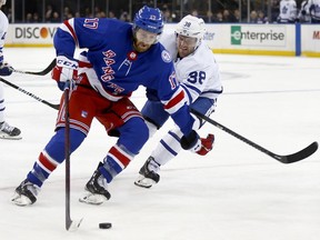 New York Rangers' Kevin Rooney skates with the puck past Toronto Maple Leafs' Rasmus Sandin during the second period of an NHL hockey game Wednesday, Jan. 19, 2022, in New York.