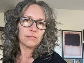 Woman with greying hair and glasses.