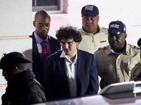 Sam Bankman-Fried, who founded and led FTX until a liquidity crunch forced the cryptocurrency exchange to declare bankruptcy, is escorted out of the Magistrate Court building after his arrest, in Nassau, Bahamas December 13, 2022.