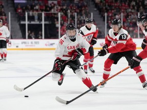 Canada's Connor Bedard, left, skates past Austria's Lukas Horl, right, and Luca Auer during second period IIHF World Junior Hockey Championship action in Halifax, Thursday, Dec. 29, 2022.