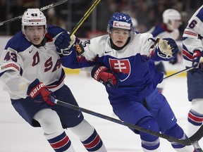 USA's Luke Hughes, left, tries to hold back Slovakia's Adam Sykora during first-period IIHF World Junior Hockey Championship hockey action in Moncton, N.B., on Wednesday, Dec. 28, 2022.