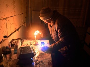 An elderly woman lights a candle in her apartment in a residential building, partially destroyed as a result of Russia's shelling in February, when Russia first invaded Ukraine, in Gorenka village, Kyiv region on Dec. 13, 2022.