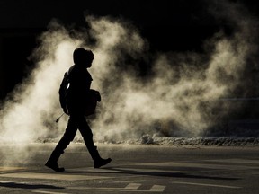 A man is silhouetted from steam from a underground grate as he makes his way through the crisp cold morning in Toronto on Dec. 14, 2016.