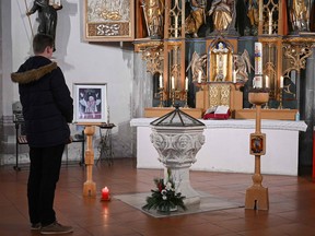 A man looks at picture of Pope Emeritus Benedict XVI, placed in the church in Marktl, Germany, on December 28, 2022.