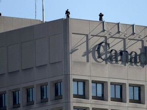 Police teams conduct surveillance above the Department of National Defence headquarters before the Remembrance Day ceremony at the National War Memorial in Ottawa on Tuesday, Nov. 11, 2014.