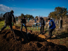 A war crimes prosecutor (right), police officers and local residents exhume the remains of Nadiya Medvidyiva, 58-year-old, killed on September 18, 2022 during the Russian invasion, at the cemetery of Pravdyne, near Kherson, southern Ukraine, on December 29, 2022.