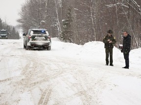 A Vermont State Trooper, centre, speaks to a homeowner Thursday, Jan. 8, 2018, near an area on Peacham Road, in Barnet, Vt., where the body of Gregory Davis was found.